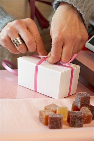 simsearch:700-06531931,k - Close-Up of Woman's Hands Tying Bow on Small White Gift Box in Shop, with Candies in Foreground, Paris, France Stock Photo - Rights-Managed, Code: 700-06531929
