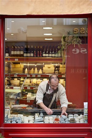 sales representative not headset - male shopkeeper arranging fresh wedges and rounds of French goat cheese in artisan cheese shop window, La Fromagerie, Paris, France Stock Photo - Rights-Managed, Code: 700-06531951