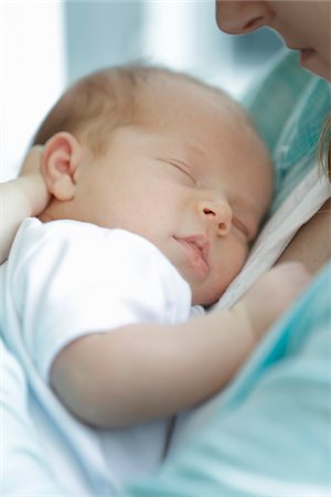 newborn baby girl in a white undershirt sleeping in the arms of mother wearing a blue shirt Stockbilder - Lizenzpflichtiges, Bildnummer: 700-06532017