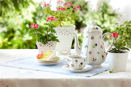 tablesetting with tea, teacup, teapot, cake, and edible geraniums as well as potted flowering geraniums in a garden setting Stock Photo - Rights-Managed, Code: 700-06532026