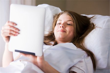 Woman lying on bed in her bedroom using digital tablet computer Foto de stock - Con derechos protegidos, Código: 700-06553307