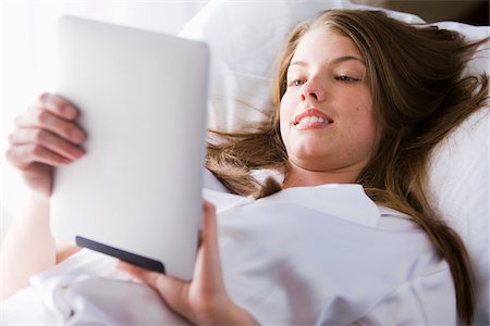 Woman lying on bed in her bedroom using digital tablet computer Stockbilder - Lizenzpflichtiges, Bildnummer: 700-06553308
