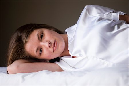 Portrait of woman lying on her bed in her bedroom. Photographie de stock - Rights-Managed, Code: 700-06553301