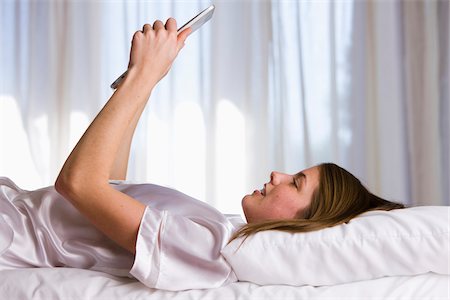 silk curtain - Woman lying on bed in her bedroom using an ipad. Stock Photo - Rights-Managed, Code: 700-06674975