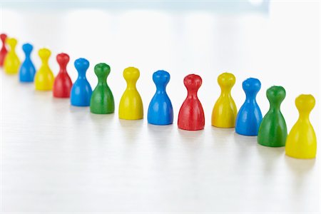 Multi-colored people-like playing pieces in a row on white background Photographie de stock - Rights-Managed, Code: 700-06679361