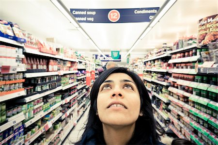 Indian woman in supermarket aisle looks up thinking Foto de stock - Con derechos protegidos, Código: 700-06752256