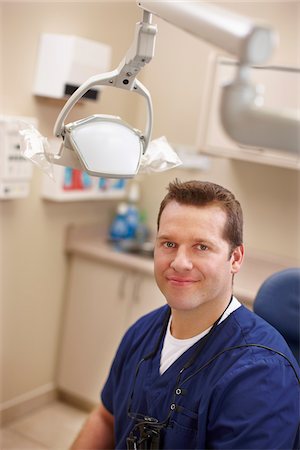 Portrait of male dentist in a chair in the examination room with swivel light in view. Photographie de stock - Rights-Managed, Code: 700-06786926