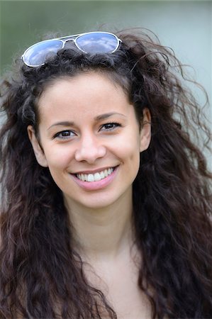 Portrait of a young woman with curly hair wearing sunglasses on head outdoors in spring, Germany Foto de stock - Con derechos protegidos, Código: 700-06808847