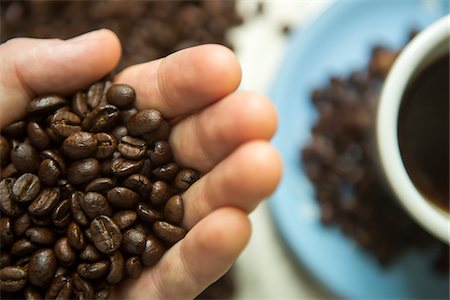 Hand Holding Coffee Beans with Cup and Saucer in Background Stockbilder - Lizenzpflichtiges, Bildnummer: 700-06808895