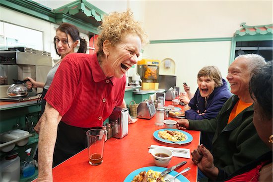 Waitress with curly red hair learning over counter and enjoying a joke with her customers, three senior citizens. A younger waitress, holding a caraffe of coffee, looks on from behind with a doubtful expression, in breakfast coffee shop in California. Photographie de stock - Premium Droits Gérés, Artiste: Mitch Tobias, Le code de l’image : 700-06803879