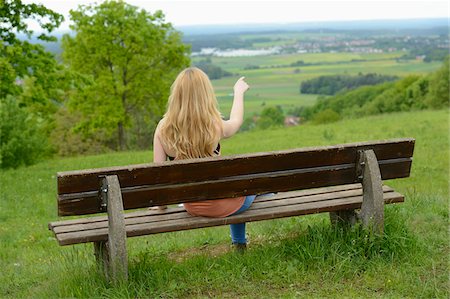 rückseite - Rear View of Young Woman Sitting on Bench and Pointing into the Distance, Germany Stockbilder - Lizenzpflichtiges, Bildnummer: 700-06841503