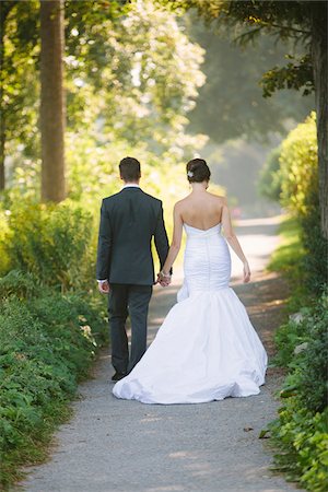 simsearch:700-05786479,k - Backview of Bride and Groom holding hands, walking down pathway outdoors, on Wedding Day Stockbilder - Lizenzpflichtiges, Bildnummer: 700-06939705