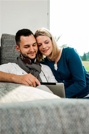 Young Couple using Tablet Computer on Sofa in Living Room, Mannheim, Baden-Wurttemberg, Germany Stock Photo - Rights-Managed, Code: 700-06962018