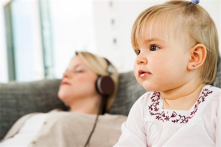 Baby Girl with Mother Listening to Music through Headphones in the background, Mannheim, Baden-Wurttemberg, Germany Foto de stock - Con derechos protegidos, Código: 700-06962012