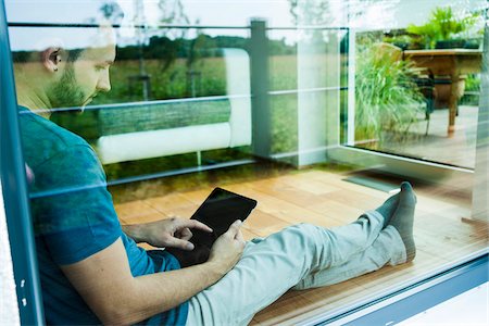 european home - Young Man Sitting on Floor at Home using Tablet Computer, Mannheim, Baden-Wurttemberg, Germany Photographie de stock - Rights-Managed, Code: 700-06962064