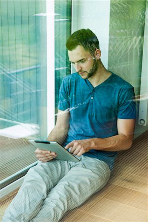 sitting on floor - Young Man Sitting on Floor at Home using Tablet Computer, Mannheim, Baden-Wurttemberg, Germany Stock Photo - Rights-Managed, Code: 700-06962065