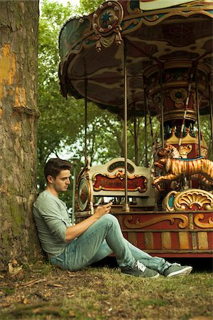 roundabout - Young Man using Cell Phone while Sitting near Carousel, Mannheim, Baden-Wurttemberg, Germany Stock Photo - Rights-Managed, Code: 700-06962071