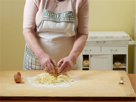 ravioli - Elderly Italian woman making dough by hand in kitchen, cracking eggs into flour, Ontario, Canada Foto de stock - Direito Controlado, Número: 700-07108329