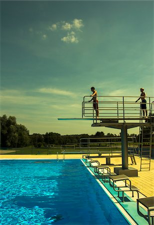 Teenage Boys Jumping into Swimming Pool from Diving Board, Langenbeutingen, Baden-Wurttemberg, Germany Foto de stock - Con derechos protegidos, Código: 700-07117303