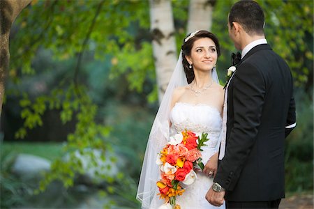 Portrait of bride and groom standing outdoors next to trees in public garden, smiling and looking at each other, in Autumn, Ontario, Canada Photographie de stock - Rights-Managed, Code: 700-07199865