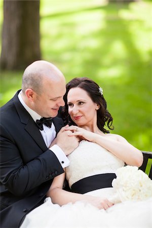 Portrait of bride and groom sitting outdoors in garden, holding hand, smiling and looking at each other, Ontario, Canada Stockbilder - Lizenzpflichtiges, Bildnummer: 700-07199878