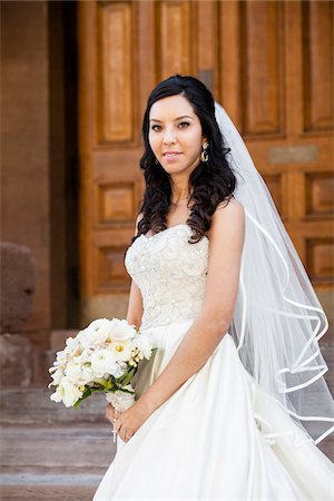 simsearch:614-03763870,k - Close-up portrait of Bride in wedding gown holding bridal bouquet, standing on stairs in front of building, smiling and looking at camera on Wedding Day, Canada Stockbilder - Lizenzpflichtiges, Bildnummer: 700-07237617