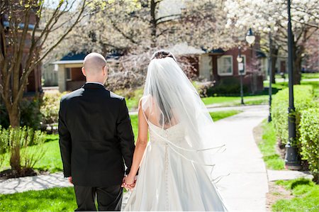 simsearch:700-06939704,k - Close-up of backview of bride in wedding gown with bridegroom, holding hands and walking down pathway in park in Spring on Wedding Day, Canada Photographie de stock - Rights-Managed, Code: 700-07237627