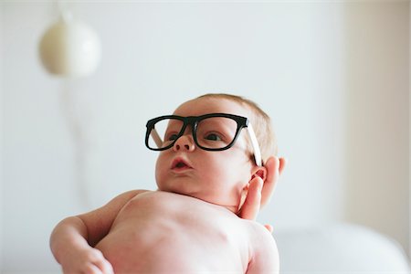 fascinado - Three week old baby boy wearing glasses and being held in mother's hand inside home, USA Foto de stock - Con derechos protegidos, Código: 700-07240915