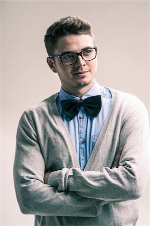 serious young adult portrait - Close-up portrait of student, young man wearing bow tie and eyeglasses with arms crossed, studio shot on white background Stock Photo - Rights-Managed, Code: 700-07278862