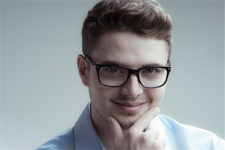 eyeglasses closeup - Close-up portrait of young man wearing eyeglasses and blue shirt, smiling and looking at camera, studio shot on white background Stock Photo - Rights-Managed, Code: 700-07278873