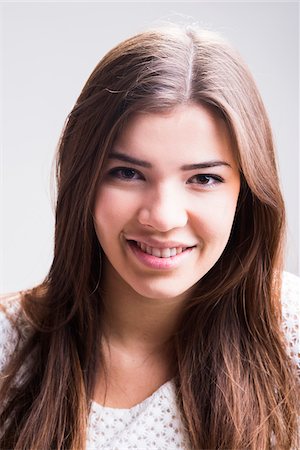 simsearch:700-07567431,k - Close-up portrait of young woman with long, brown hair, smiling and looking at camera, studio shot on white background Foto de stock - Con derechos protegidos, Código: 700-07278965