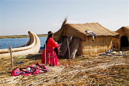 Woman in Peruvian clothing standing next to straw house, Floating Island of Uros, Lake Titicaca, Peru Stockbilder - Lizenzpflichtiges, Bildnummer: 700-07529097