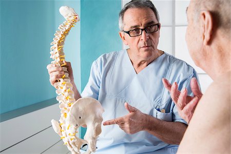 Senior, male doctor discussin spinal cord with senior, male patient, in office, Germany Stockbilder - Lizenzpflichtiges, Bildnummer: 700-07529248