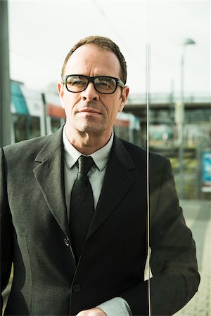 Portrait of businessman wearing glasses, standing at train station outdoors, Mannheim, Germany Stock Photo - Rights-Managed, Code: 700-07529275
