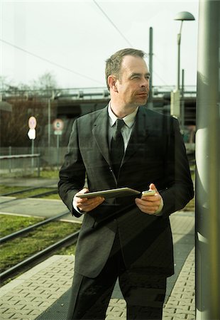 Portrait of businessman holding cell phone and tablet computer, standing at train station outdoors, Mannheim, Germany Stockbilder - Lizenzpflichtiges, Bildnummer: 700-07529273