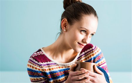 Close-up portrait of teenage girl with hair in bun, holding mug and looking to the side, studio shot on blue background Photographie de stock - Rights-Managed, Code: 700-07567438