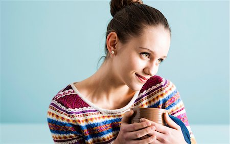 simsearch:700-07567449,k - Close-up portrait of teenage girl with hair in bun, holding mug and looking to the side, studio shot on blue background Stockbilder - Lizenzpflichtiges, Bildnummer: 700-07567438