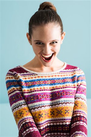 portrait of young woman caucasian one person - Close-up portrait of teenage girl with hair in bun, looking at camera and smiling with open mouth, studio shot on blue background Stock Photo - Rights-Managed, Code: 700-07567444