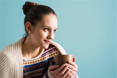 simsearch:700-07567446,k - Close-up portrait of teenage girl with hair in bun, holding mug and looking into the distance, studio shot on blue background Foto de stock - Con derechos protegidos, Código: 700-07567440