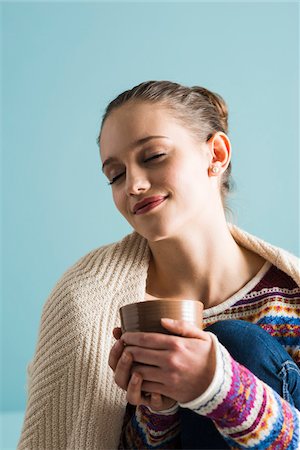 Close-up portrait of teenage girl holding mug with eyes closed, studio shot on blue background Foto de stock - Con derechos protegidos, Código: 700-07567442