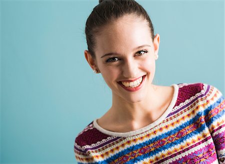 simsearch:700-07567431,k - Close-up portrait of teenage girl, looking at camera and smiling, studio shot on blue background Foto de stock - Con derechos protegidos, Código: 700-07567450