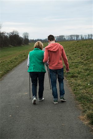 Backview of teenage grandson with grandmother using walker on pathway in park, walking in nature, Germany Foto de stock - Con derechos protegidos, Código: 700-07584830