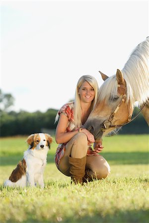ponerse en cuclillas - Close-up portrait of a young woman with her Haflinger horse and her Kooikerhondje puppy in summer, Upper Palatinate, Bavaria, Germany Foto de stock - Con derechos protegidos, Código: 700-07734350