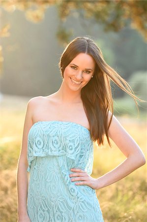 dress blowing - Portrait of young woman standing in a meadow at sunset in early autumn, looking at camera and smiling, Bavaria, Gremany Foto de stock - Con derechos protegidos, Código: 700-07760227