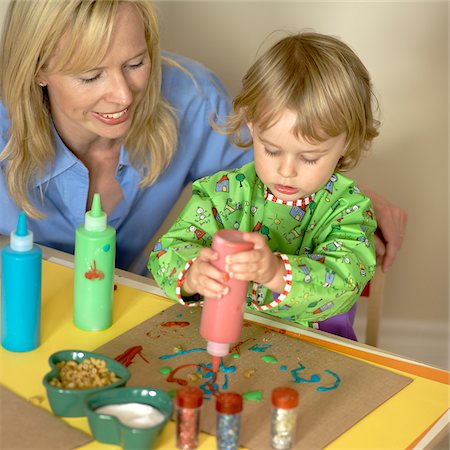 Mother sitting with young daughter creating art work, arts and crafts at home Foto de stock - Con derechos protegidos, Código: 700-07784469