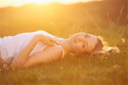 Young woman lying on a meadow at sunset in spring, Germany Stock Photo - Rights-Managed, Code: 700-08080555