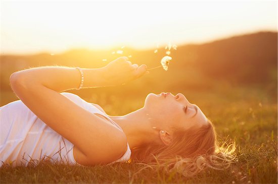 Young woman holding a dandelion in her hand lying on a meadow at sunset in spring, Germany Photographie de stock - Premium Droits Gérés, Artiste: David & Micha Sheldon, Le code de l’image : 700-08080556