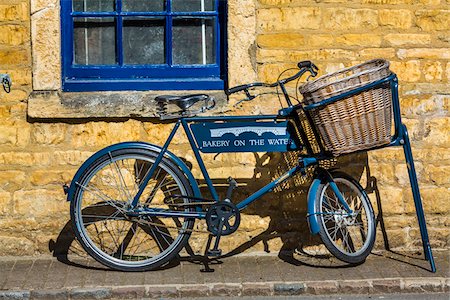 Close-up of bicycle with wicker basket basket parked on sidewalk, Bourton-on-the-Water, Gloucestershire, The Cotswolds, England, United Kingdom Foto de stock - Con derechos protegidos, Código: 700-08122111