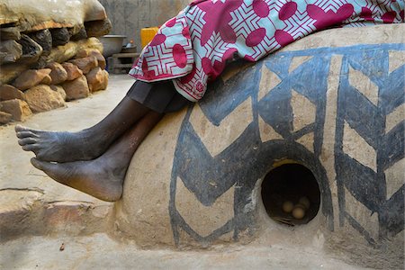 fuchsia - Close-up of woman's legs and feet, sitting on decorated round henhouse with eggs, Tiebele, Burkina Faso Photographie de stock - Rights-Managed, Code: 700-08171609