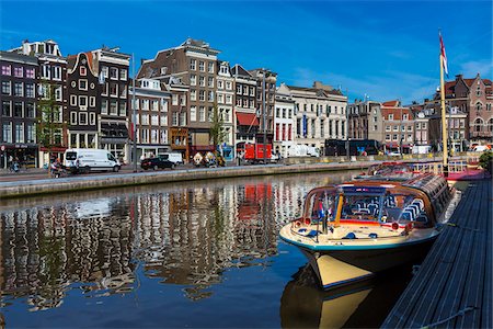 Typical buildings line the street with a tour boat moored along the seawall of the Oudezijds Voorburgwal canal in Amsterdam, Holland Stock Photo - Rights-Managed, Code: 700-08973536
